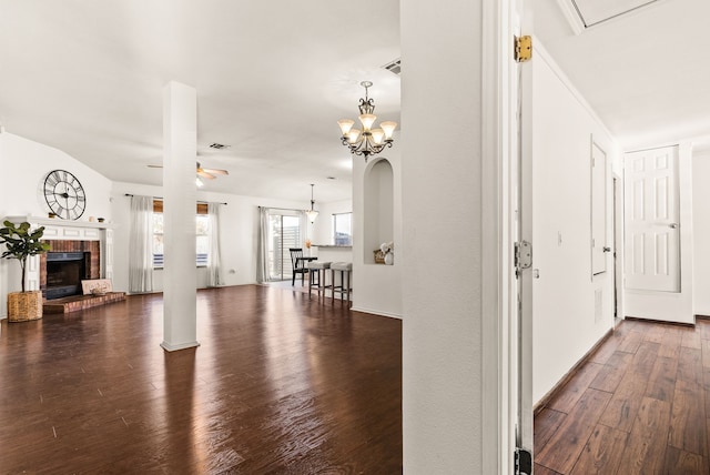 unfurnished living room featuring a fireplace, ceiling fan with notable chandelier, and hardwood / wood-style flooring