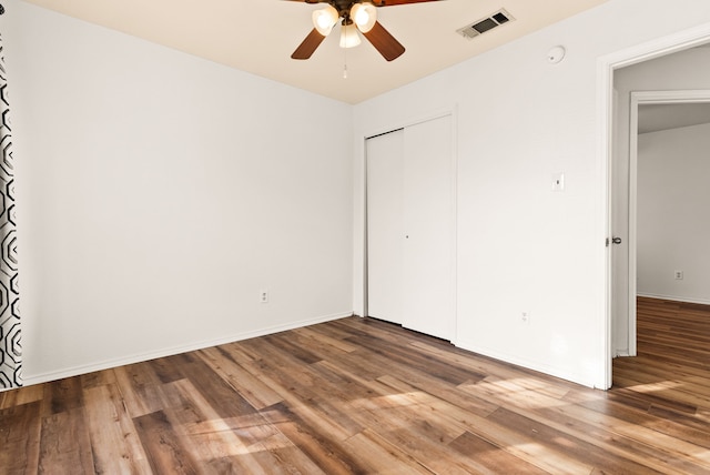 unfurnished bedroom with hardwood / wood-style floors, a closet, and ceiling fan