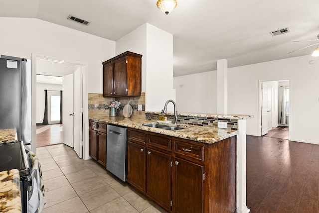 kitchen featuring backsplash, sink, appliances with stainless steel finishes, light stone counters, and kitchen peninsula