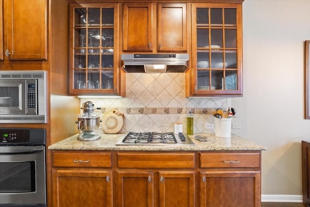 kitchen with tasteful backsplash, light stone countertops, and stainless steel appliances