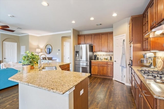 kitchen with sink, stainless steel appliances, dark hardwood / wood-style floors, light stone countertops, and an island with sink