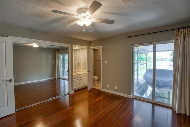 unfurnished bedroom with ensuite bathroom, access to exterior, ceiling fan, and dark hardwood / wood-style floors