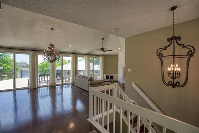 living room featuring a textured ceiling, a water view, ceiling fan, hardwood / wood-style flooring, and floor to ceiling windows