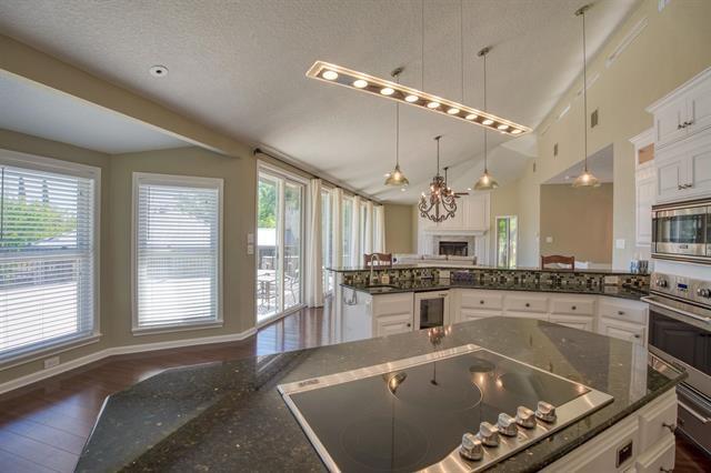 kitchen featuring dark stone countertops, hanging light fixtures, stainless steel appliances, dark hardwood / wood-style flooring, and white cabinetry