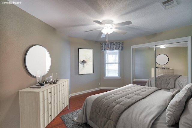 bedroom featuring dark wood-type flooring, a textured ceiling, and ceiling fan