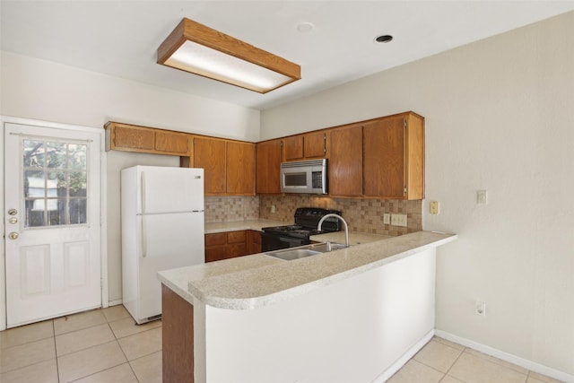 kitchen featuring kitchen peninsula, sink, white fridge, and black electric range