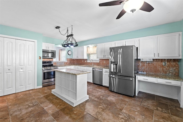 kitchen featuring white cabinetry, sink, pendant lighting, a kitchen island, and appliances with stainless steel finishes