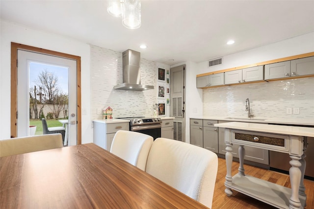 kitchen with backsplash, electric range, sink, and wall chimney exhaust hood