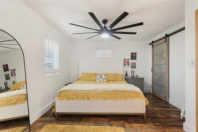 bedroom with ceiling fan, a barn door, and dark hardwood / wood-style floors