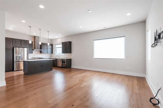 kitchen with decorative backsplash, wall chimney exhaust hood, pendant lighting, stainless steel fridge with ice dispenser, and a kitchen island