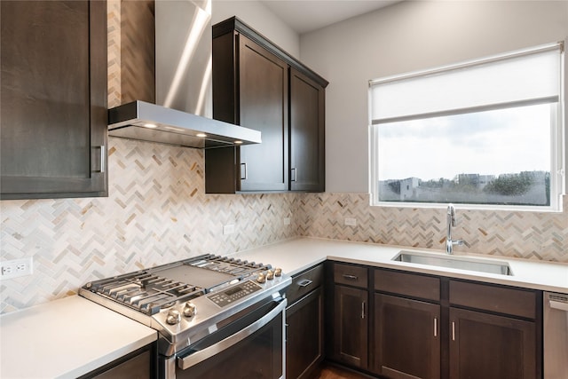 kitchen featuring backsplash, dark brown cabinetry, stainless steel appliances, sink, and wall chimney range hood