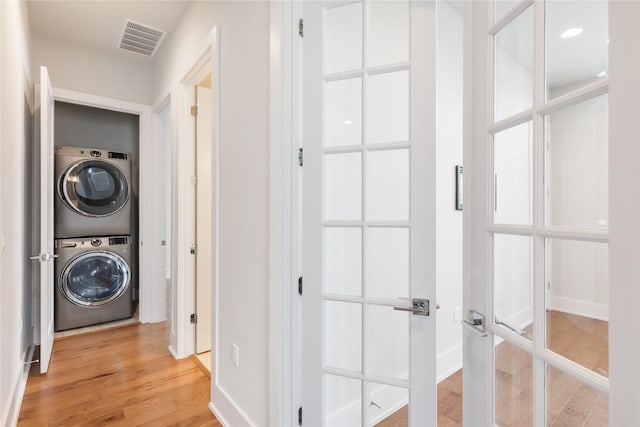 laundry area with hardwood / wood-style flooring and stacked washing maching and dryer