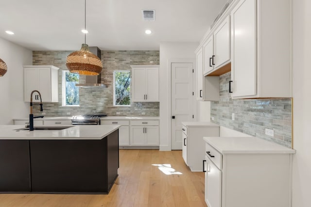 kitchen featuring white cabinetry, sink, gas range, and decorative light fixtures