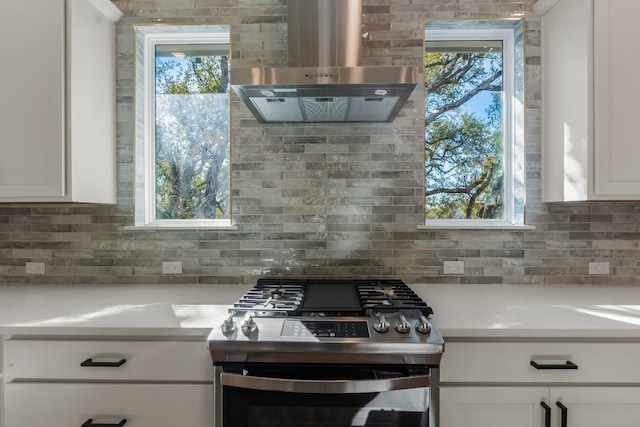 kitchen with gas range, white cabinets, backsplash, and wall chimney exhaust hood