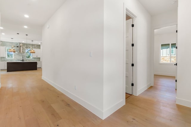 corridor with sink and light hardwood / wood-style floors