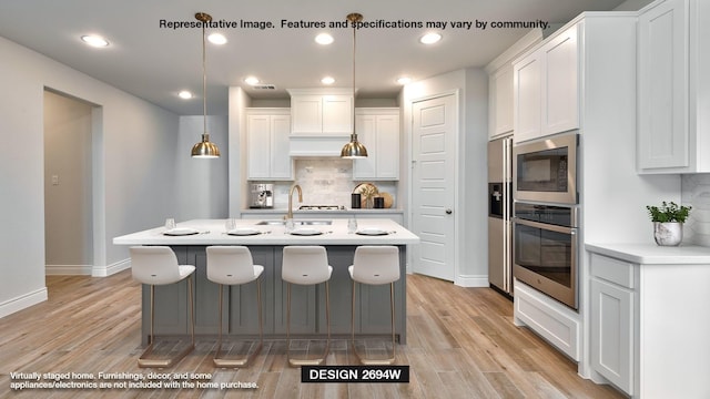 kitchen featuring white cabinetry, decorative light fixtures, decorative backsplash, appliances with stainless steel finishes, and light wood-type flooring