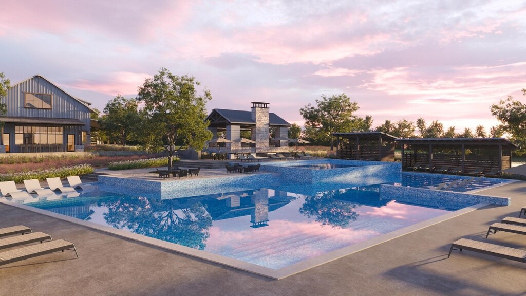 pool at dusk featuring a patio and a hot tub