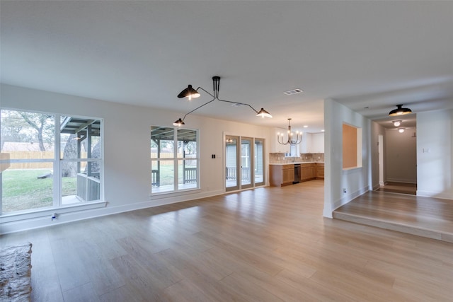 unfurnished living room with light hardwood / wood-style flooring and a chandelier