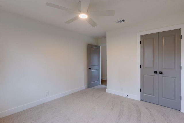 unfurnished bedroom featuring ceiling fan, a closet, and light carpet