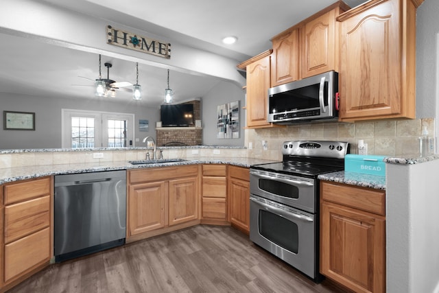 kitchen with ceiling fan, sink, stainless steel appliances, light stone counters, and backsplash