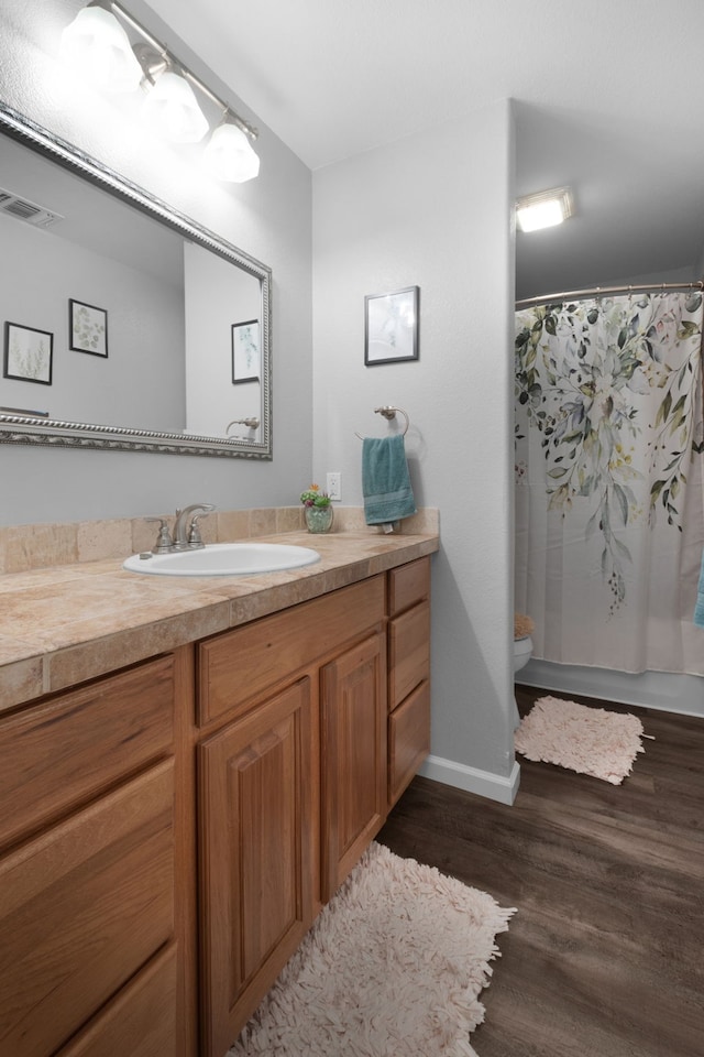 bathroom featuring a shower with shower curtain, wood-type flooring, vanity, and toilet