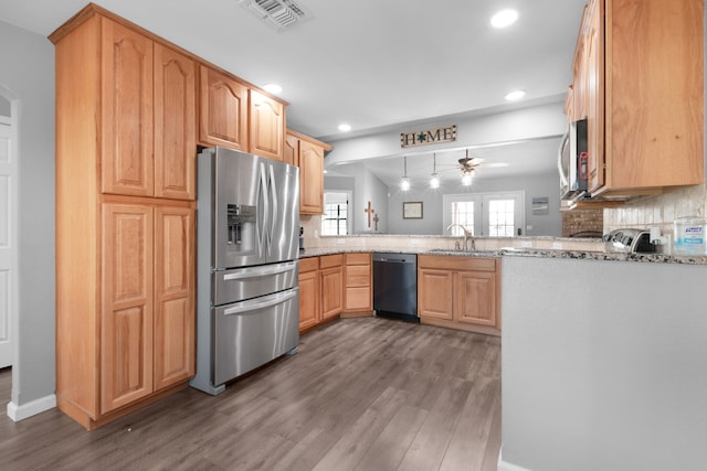 kitchen featuring decorative backsplash, ceiling fan, light stone counters, kitchen peninsula, and stainless steel appliances