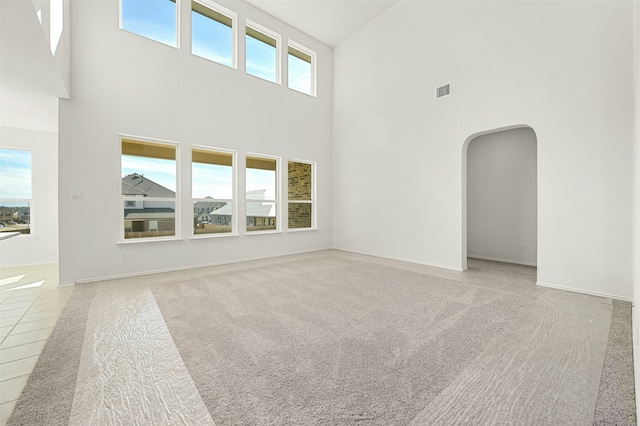 unfurnished living room featuring a towering ceiling and a healthy amount of sunlight