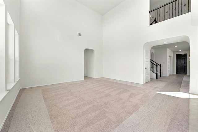 empty room with a high ceiling and light colored carpet