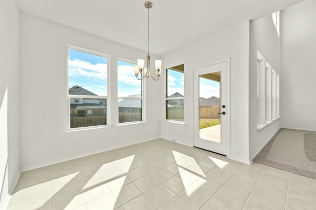 unfurnished dining area with a notable chandelier, light tile patterned flooring, and a wealth of natural light