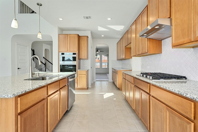 kitchen with stainless steel appliances, sink, ceiling fan, an island with sink, and pendant lighting