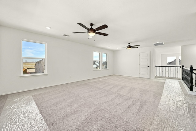 carpeted empty room with ceiling fan and plenty of natural light