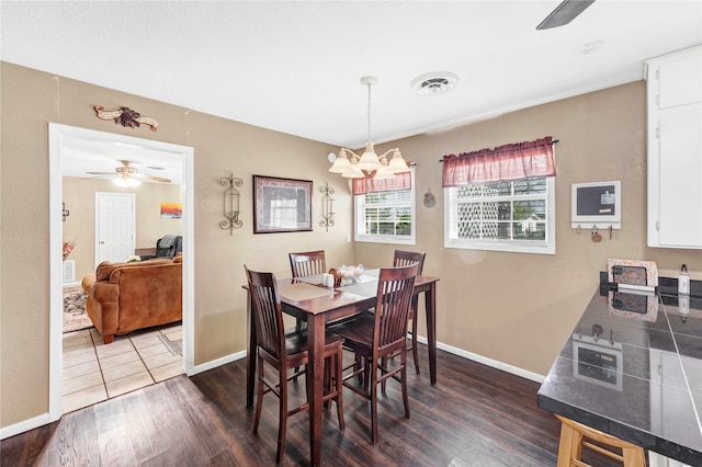 dining area featuring dark hardwood / wood-style flooring and ceiling fan with notable chandelier