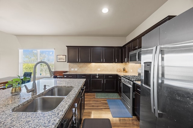 kitchen featuring sink, dark brown cabinets, light stone countertops, and appliances with stainless steel finishes