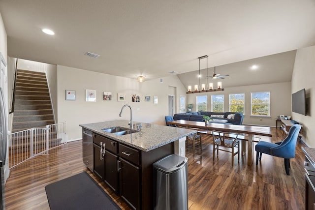 kitchen featuring sink, dark wood-type flooring, light stone counters, an island with sink, and stainless steel dishwasher