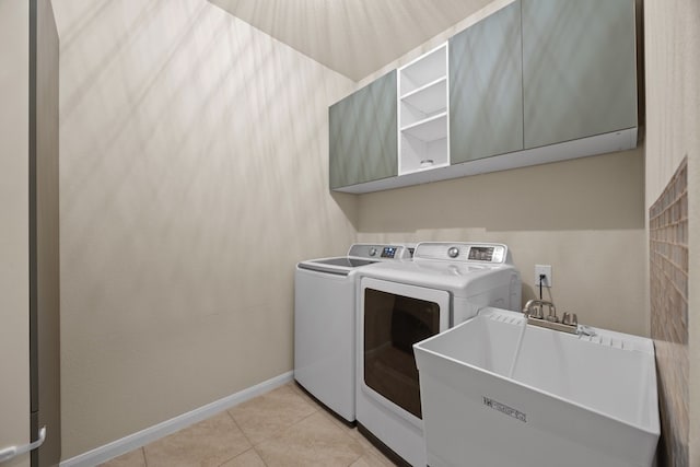 laundry area with sink, light tile patterned floors, washer and clothes dryer, and cabinets