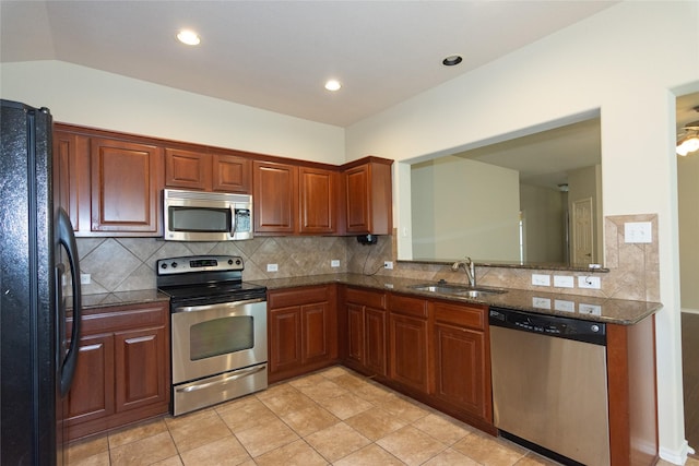 kitchen featuring sink, dark stone countertops, tasteful backsplash, light tile patterned flooring, and stainless steel appliances