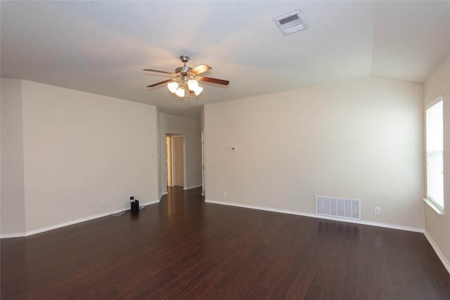 empty room featuring a healthy amount of sunlight, vaulted ceiling, ceiling fan, and dark wood-type flooring