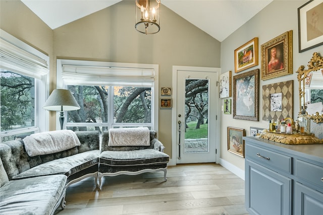 sitting room featuring a chandelier, a healthy amount of sunlight, vaulted ceiling, and light wood-type flooring