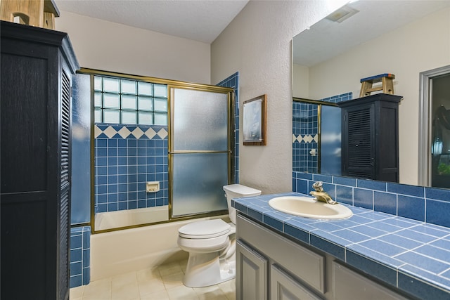 full bathroom featuring tile patterned floors, vanity, bath / shower combo with glass door, and toilet