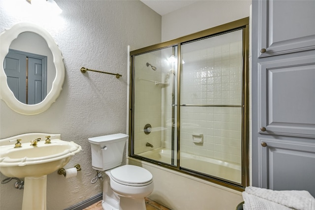 222 Winn Valley Dr, Wimberley, TX 78676 - full bath with a textured wall, shower / bath combination with glass door, toilet, and a sink