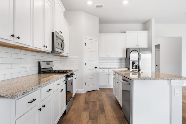 kitchen with white cabinets, appliances with stainless steel finishes, and an island with sink