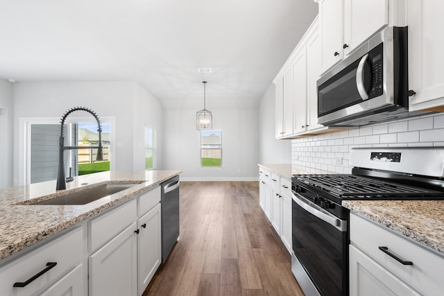 kitchen featuring white cabinetry, sink, hanging light fixtures, and appliances with stainless steel finishes