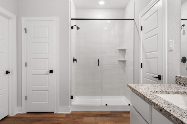 bathroom with wood-type flooring, vanity, and a shower with door