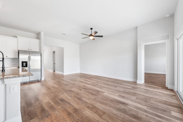 kitchen with backsplash, white cabinets, ceiling fan, light stone countertops, and stainless steel fridge with ice dispenser