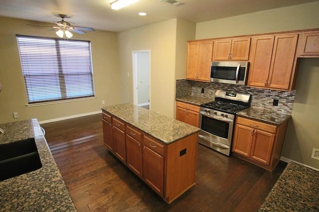 kitchen featuring dark wood-type flooring, appliances with stainless steel finishes, stone countertops, and decorative backsplash