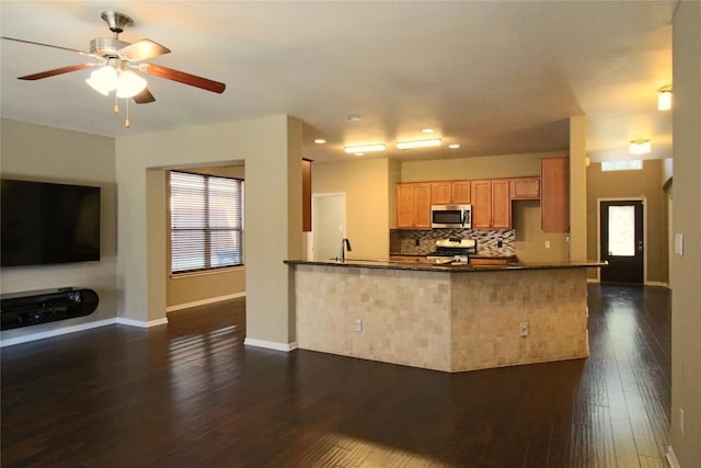 kitchen featuring stove, backsplash, dark hardwood / wood-style floors, and kitchen peninsula