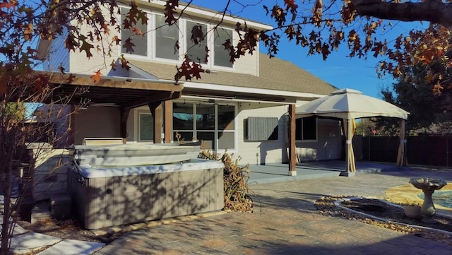 rear view of house with a hot tub and a patio