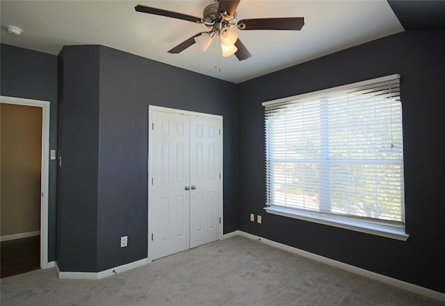 unfurnished bedroom featuring ceiling fan, light colored carpet, and a closet