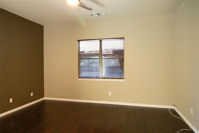 spare room featuring dark wood-type flooring and ceiling fan