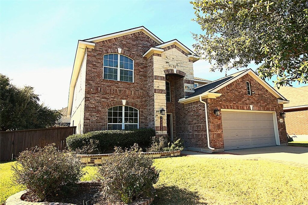2609 Saddle Blanket Pl, Leander, TX 78641 - traditional home featuring fence, brick siding, a front yard, and a garage